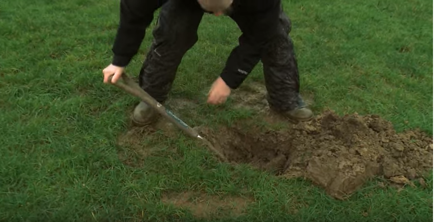 a person digging a hole in the grass